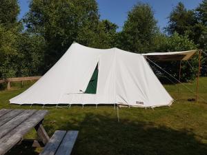 Tenda bianca in un campo con tavolo da picnic di Ameland tentenverhuur Ameland a Nes