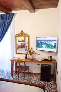 Zimmer mit einem Schreibtisch, einem Spiegel und einem Tisch. in der Unterkunft Suite Nettuno Paestum in Paestum