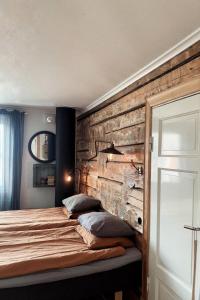 a bedroom with a wooden wall and a bed with pillows at Pensionatet in Piteå