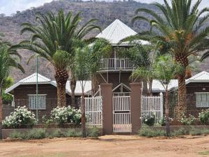 a house with palm trees and a white fence at DE JAGTER'S NEST in Otavi