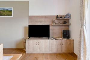 a living room with a television on a wooden cabinet at Schererhof Dolomitenblick in Castelrotto