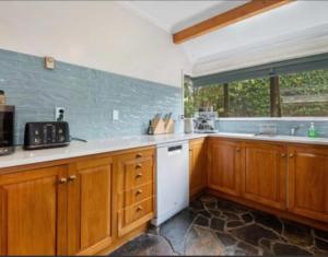 a kitchen with wooden cabinets and a white dishwasher at Young Woods Lodge in Rotorua