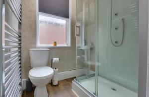 a bathroom with a toilet and a shower and a window at Home from Home 4-Bed Townhouse - Ideal for Families, Groups & Contractors, Free Parking, Pet Friendly, Netflix in Walkly