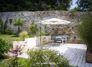 une terrasse avec une table et un parasol dans l'établissement Ty Puns - Gîte écoresponsable dans un espace verdoyant en centre-ville, à Morlaix