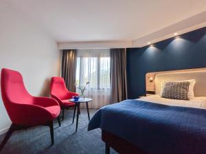 Una habitación de hotel con una cama y dos sillas rojas. en Good Morning + Helsingborg, en Helsingborg