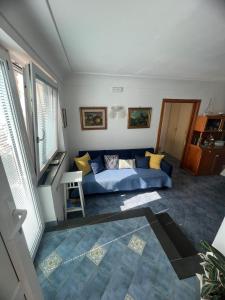 sala de estar con sofá azul y ventanas en Appartamento La Follicara en Anacapri