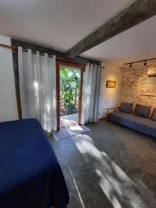 Habitación con cama, sofá y ventana en Estudio Lirios seu cantinho ecológico na natureza en Marau
