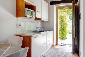 una cocina con armarios blancos y una puerta a un patio en La Corte di Langa alloggio Quarzo, en Albaretto Della Torre 