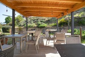 eine Terrasse mit Tischen und Stühlen unter einem Holzdach in der Unterkunft La Corte di Langa alloggio Quarzo in Albaretto Della Torre 