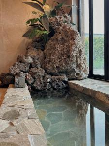 a pool of water in a room with a rock wall at 제주 전통 구옥을 현대식으로 해석한 Stay EUNWOL-OJO in Seogwipo