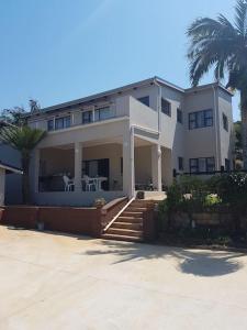 a large white house with a palm tree in front of it at 4 Bedroom house with lovely sea views. in Ballito