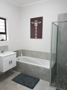 a bathroom with a tub and a giraffe picture on the wall at 4 Bedroom house with lovely sea views. in Ballito