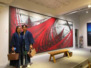 two women standing in front of a large painting at UTSUROI Tsuchiya Annex in Toyooka