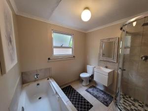 a bathroom with a tub and a toilet and a shower at Varswaterkloof Houthuis in Paarl