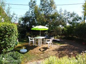 een tafel en twee stoelen en een paraplu in de tuin bij TY BIHAN in La Bernerie-en-Retz