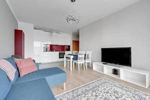 uma sala de estar com um sofá azul e uma televisão em Golden Apartments&Glamping-DG10 em Gdańsk