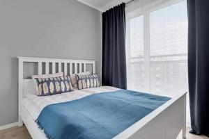 a bedroom with a white bed with blue sheets and a window at Golden Apartments&Glamping-DG10 in Gdańsk
