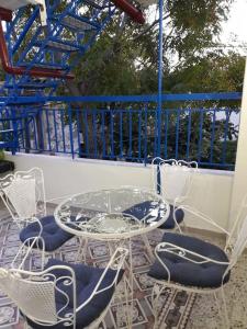y balcón con mesa de cristal y sillas. en Lovely Vacation Home, en Poros
