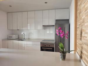 uma cozinha com um frigorífico e um vaso com flores cor-de-rosa em Acogedora casa con vistas panorámicas de vigo em Vigo
