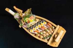 a wooden boat filled with sushi and eggs on a table at EPIC SANA Luanda Hotel in Luanda