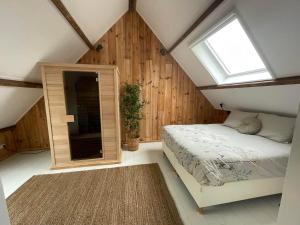 a attic bedroom with a bed and a window at B & B 'Droom in de polder de Suite met prive sauna in Arnemuiden