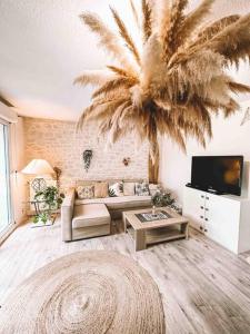a living room with a couch and a palm tree at Havre de paix, jardin, place parking proche plage in Montpellier
