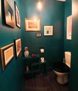 a green bathroom with a toilet and pictures on the wall at Havre de paix, jardin, place parking proche plage in Montpellier