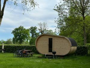 a small wooden shed in a field with a table and bicycles at Camping de Messeugne 