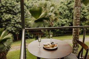 a table with a plate of food and glasses of wine at mist at Cape Tribulation in Cape Tribulation