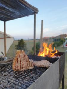 two pieces of meat on a grill with a fire at Osteria e Locanda Del Viaggiatore in Russi