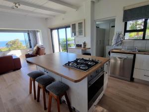 a kitchen with a stove and a table with stools at Deo-Lize in Bettyʼs Bay