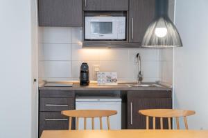 a small kitchen with two tables and a microwave at Apartamentos Ferrer Lime Playa de Alcudia in Port d'Alcudia