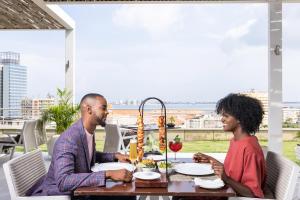 a man and a woman sitting at a table at EPIC SANA Luanda Hotel in Luanda