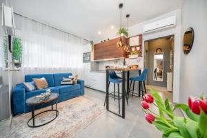 ein Wohnzimmer mit einem blauen Sofa und einer Küche in der Unterkunft Apartman Megi in Šibenik