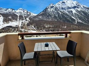 a table and chairs on a balcony with a snow covered mountain at Appartement Montgenèvre, 2 pièces, 4 personnes - FR-1-266-168 in Montgenèvre