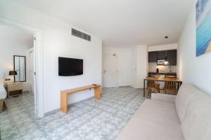 a living room with a couch and a tv on a wall at Apartamentos Ferrer Lime Playa de Alcudia in Port d'Alcudia