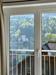 a window with a view of a lake and a house at Ferienwohnung Grundlsee in Grundlsee