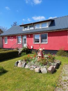 uma casa vermelha com um jardim em frente em Pension zum Meer em Breege