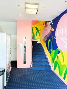 a hallway with blue carpeted stairs with a colorful wall at BALEGRA City Hotel Basel Contactless Self Check-in in Basel