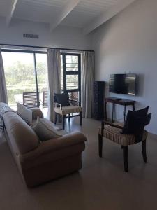 a living room with a couch and chairs and a television at 2 bed 2 bath apartment with stunning sea views. in Ballito