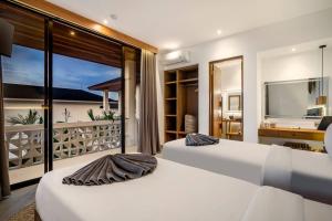 twee bedden in een slaapkamer met uitzicht op de oceaan bij Villa Arjuna by BaliSuperHost in Canggu