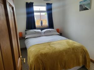 a bedroom with a bed with a yellow blanket and a window at A great place for you and your dog to stay in Falmouth