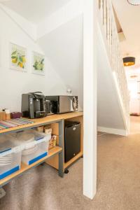 a room with a desk with a microwave and stairs at Bradstone Garden Retreat in Folkestone