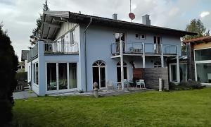 uma casa branca com uma varanda e um quintal em ciao-aschau Haus Beate em Frasdorf