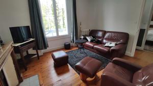 salon ze skórzaną kanapą i telewizorem w obiekcie Maison des années 30 - Vic-Sur-Cère - 4 personnes w mieście Vic-sur-Cère