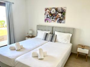 a bedroom with a large white bed with two towels at Kali Holiday Apartments in Stalís