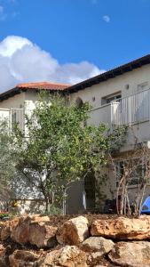 a house with a stone wall in front of a building at מול הים - בית נופש עם ממ"ד ומרפסת עם נוף פנורמי לים in Moreshet