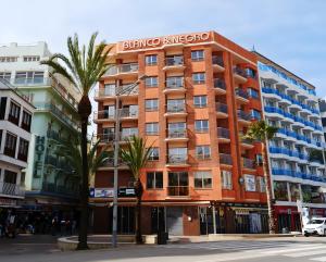 un bâtiment orange dans une rue bordée de palmiers dans l'établissement Marina Beach Apartaments, à Lloret de Mar