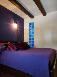 - une chambre avec un lit violet et une fenêtre dans l'établissement Raices, à Robledondo