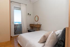 a white bedroom with a bed and a window at Zoe's apartment in Zakynthos Town